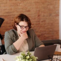 Rollstuhlfahrerin am Tisch sitzend mit Laptop